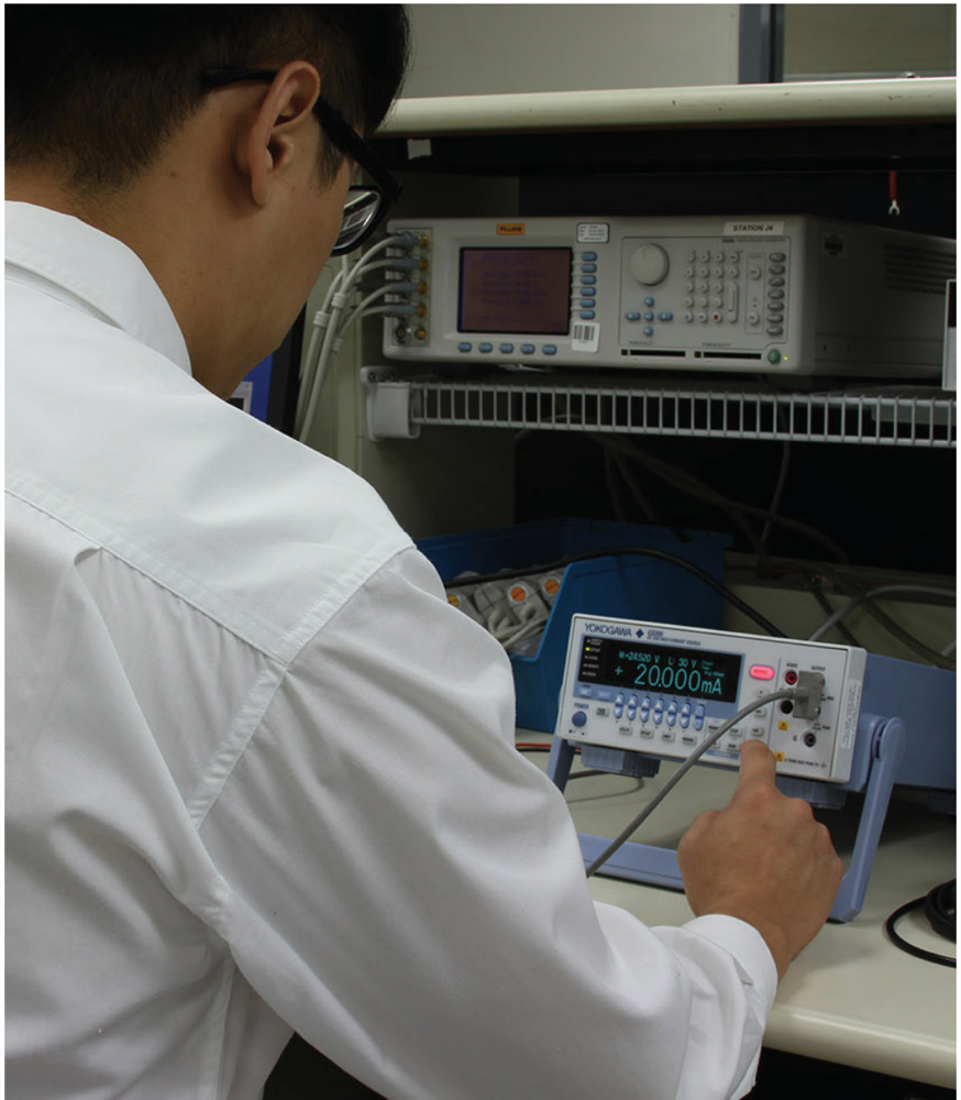Engineer testing a Yokogawa GS200 source measure unit on a test bench